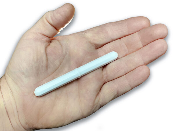 A 100mm magnetic stir bar from Obtainium Science and Surplus is resting on an open palm. The stir bar is white, cylindrical, and has a slightly hexagonal shape with tapered ends. The background is plain white, highlighting the size and shape of the stir bar in relation to the hand.